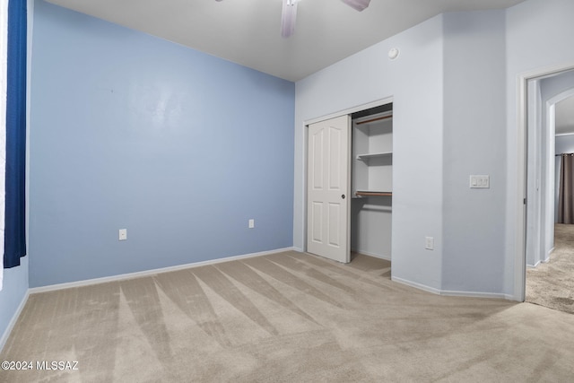 unfurnished bedroom featuring light carpet, a closet, and ceiling fan