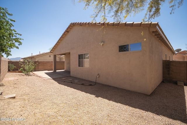 back of house with a tile roof, a patio area, a fenced backyard, and stucco siding