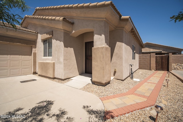 view of property exterior with an attached garage, a tile roof, fence, and stucco siding