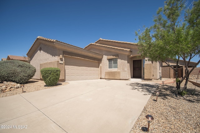 view of front of property featuring stucco siding, an attached garage, a tile roof, and driveway