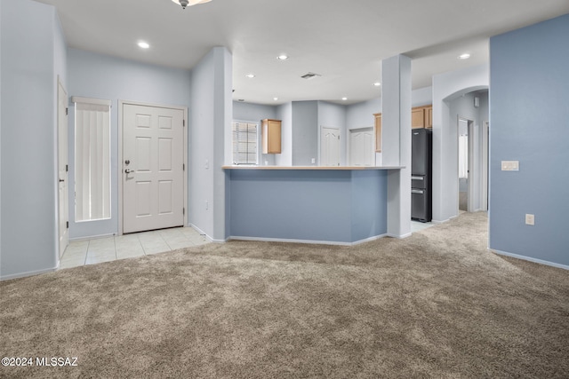 unfurnished living room with visible vents, recessed lighting, arched walkways, and light carpet