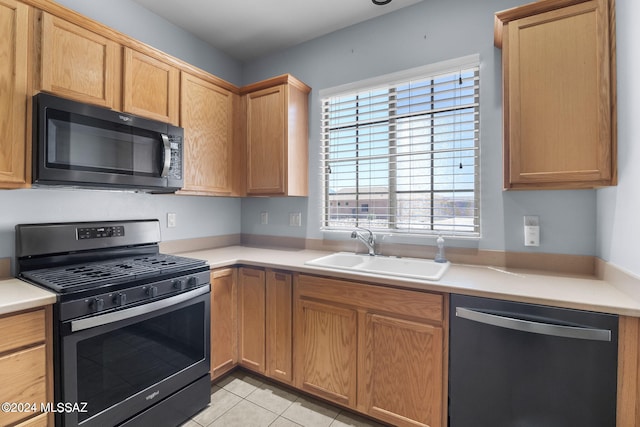 kitchen with light countertops, light tile patterned flooring, appliances with stainless steel finishes, and a sink