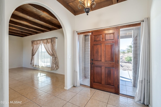 tiled entrance foyer featuring beam ceiling, wooden ceiling, and a wealth of natural light