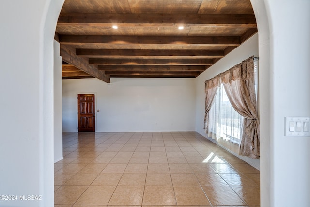 tiled empty room featuring beam ceiling and wood ceiling