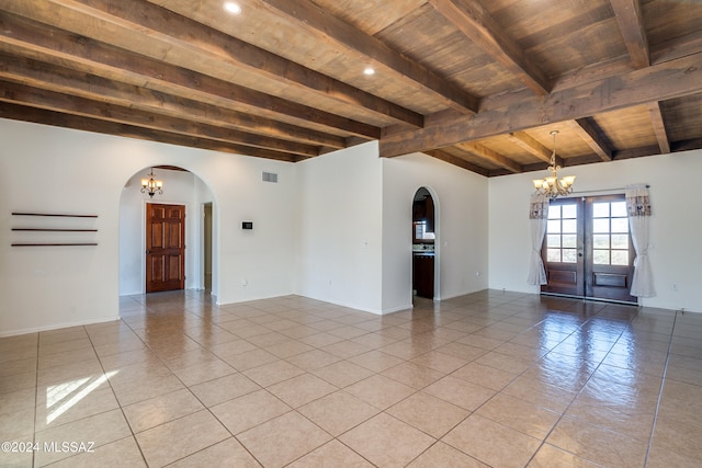 tiled empty room featuring a chandelier, beam ceiling, french doors, and wooden ceiling