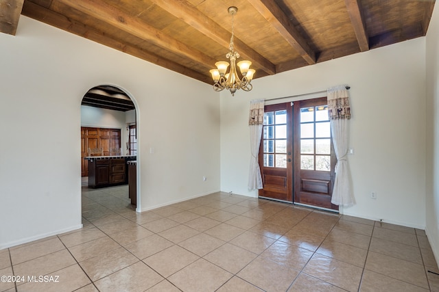 tiled spare room with beamed ceiling, a chandelier, wood ceiling, and french doors