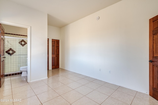 unfurnished bedroom featuring ensuite bathroom and light tile patterned flooring