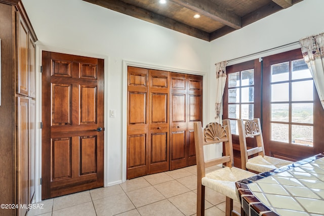 bedroom featuring beam ceiling, wood ceiling, light tile patterned floors, and multiple windows