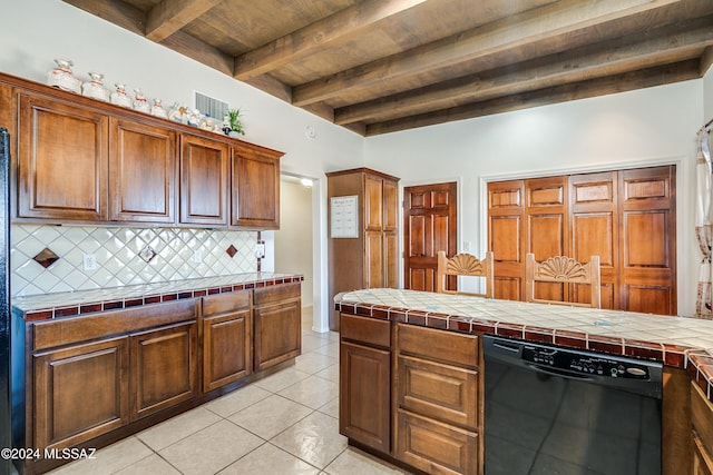 kitchen featuring tile countertops, beamed ceiling, light tile patterned flooring, and black dishwasher