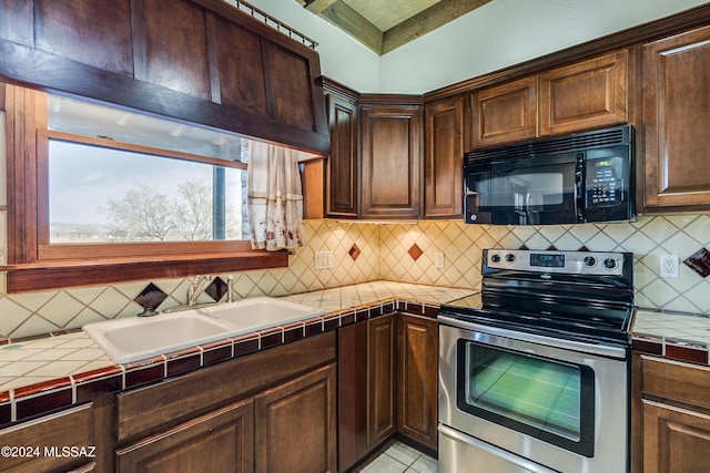 kitchen featuring dark brown cabinetry, tile counters, and stainless steel range with electric cooktop