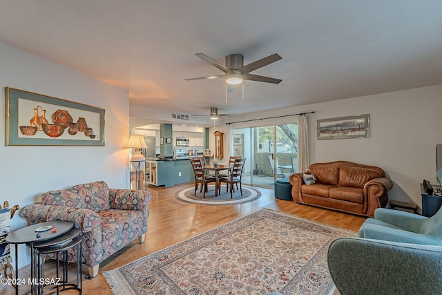 living room featuring ceiling fan and light hardwood / wood-style flooring