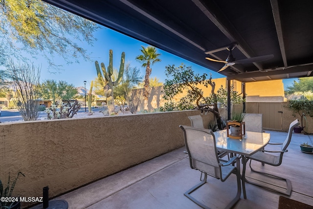 patio terrace at dusk featuring ceiling fan and a balcony