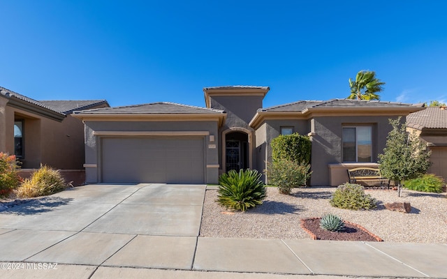 prairie-style home with an attached garage, a tile roof, concrete driveway, and stucco siding