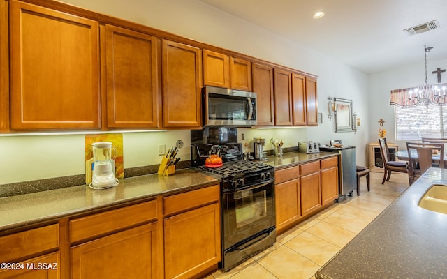 kitchen featuring black gas stove, visible vents, stainless steel microwave, and brown cabinetry