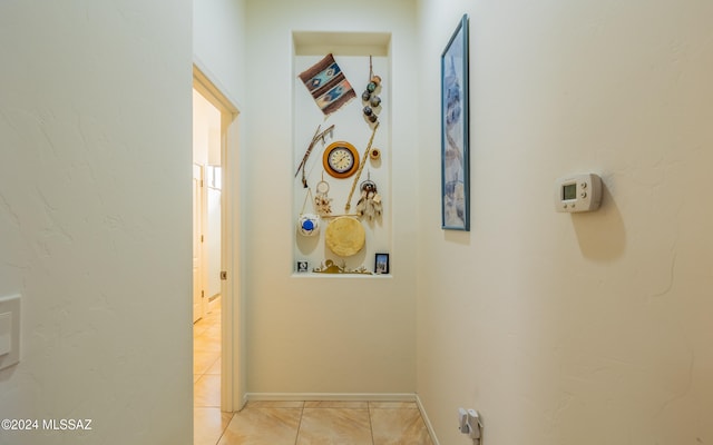 hall featuring baseboards and light tile patterned flooring