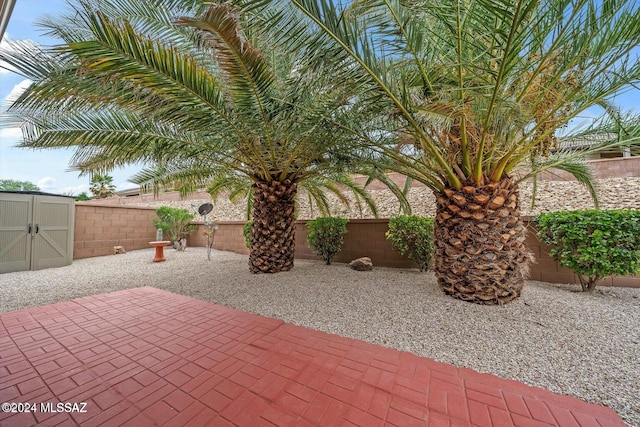 view of patio / terrace with an outbuilding, a storage unit, and a fenced backyard