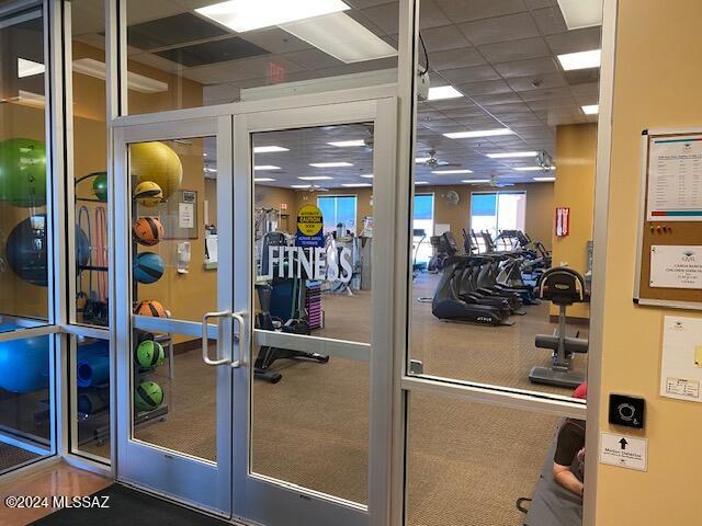 workout area featuring a paneled ceiling and french doors