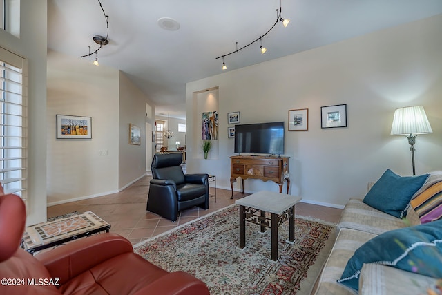 living room with rail lighting, light tile patterned flooring, and an inviting chandelier