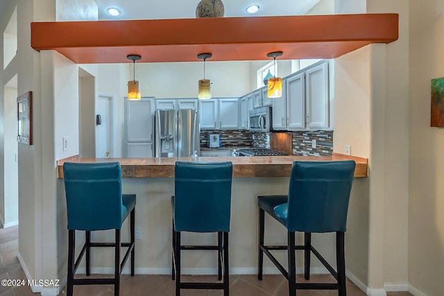 kitchen featuring a breakfast bar, decorative light fixtures, stainless steel appliances, and kitchen peninsula