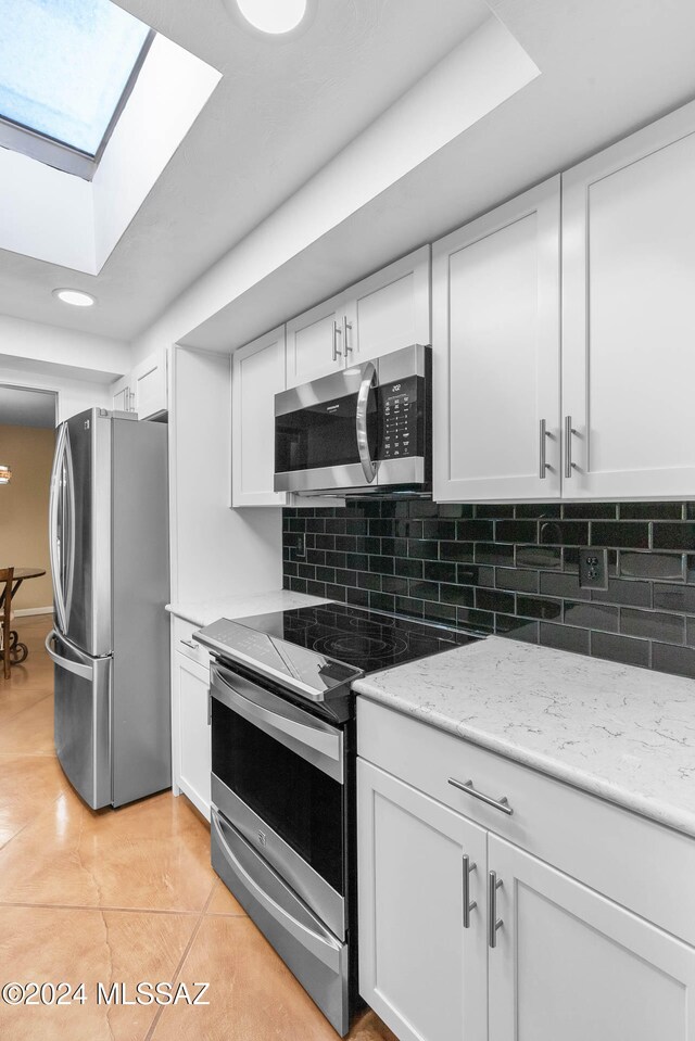 kitchen featuring white cabinets, light tile patterned floors, backsplash, and stainless steel appliances