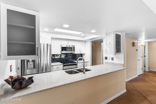 kitchen featuring white cabinets, sink, tile patterned flooring, light stone countertops, and appliances with stainless steel finishes