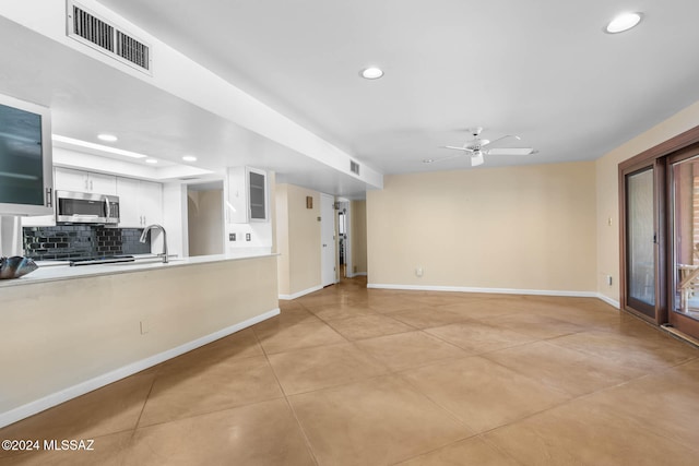 unfurnished living room with ceiling fan, sink, and light tile patterned flooring