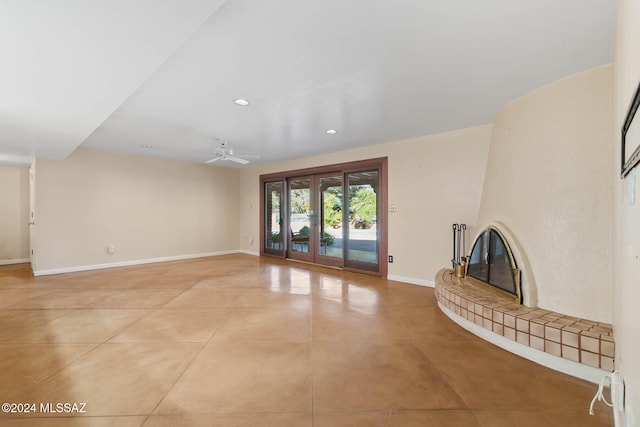 unfurnished living room with light tile patterned flooring, ceiling fan, and a tiled fireplace