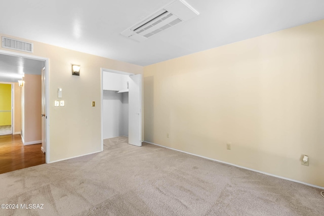 unfurnished bedroom featuring a walk in closet, light carpet, and a closet