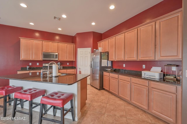 kitchen with appliances with stainless steel finishes, a sink, a kitchen breakfast bar, light brown cabinets, and recessed lighting