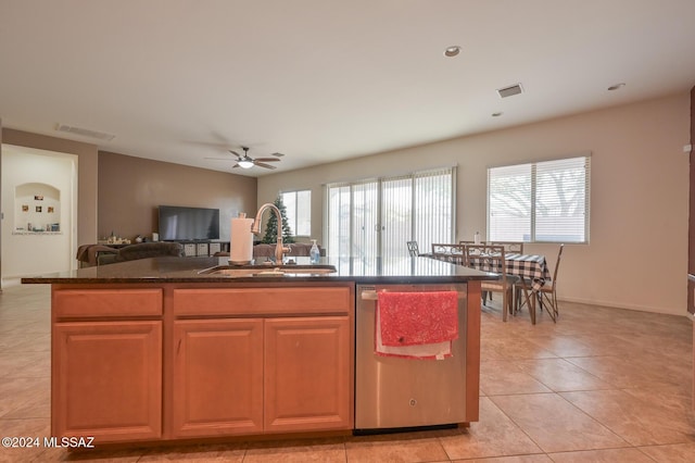 kitchen featuring a sink, stainless steel dishwasher, open floor plan, light tile patterned floors, and a kitchen island with sink