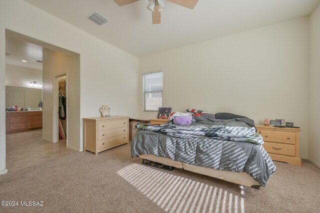bedroom featuring a walk in closet, light carpet, a ceiling fan, a closet, and baseboards