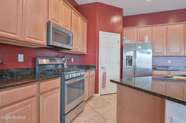 kitchen featuring stainless steel appliances, dark stone countertops, light tile patterned floors, and light brown cabinetry