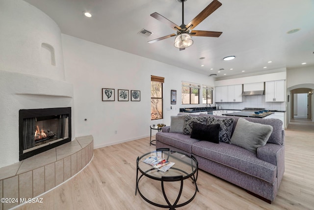 living room featuring ceiling fan, a fireplace, and light hardwood / wood-style flooring