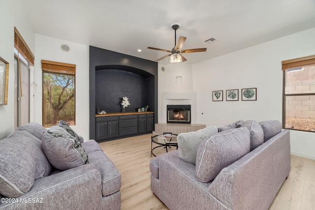 living room with ceiling fan, light hardwood / wood-style floors, and a fireplace