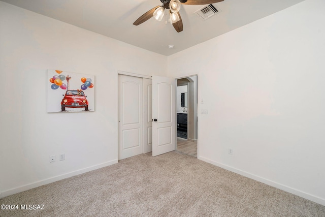 unfurnished bedroom featuring ceiling fan, light carpet, and a closet