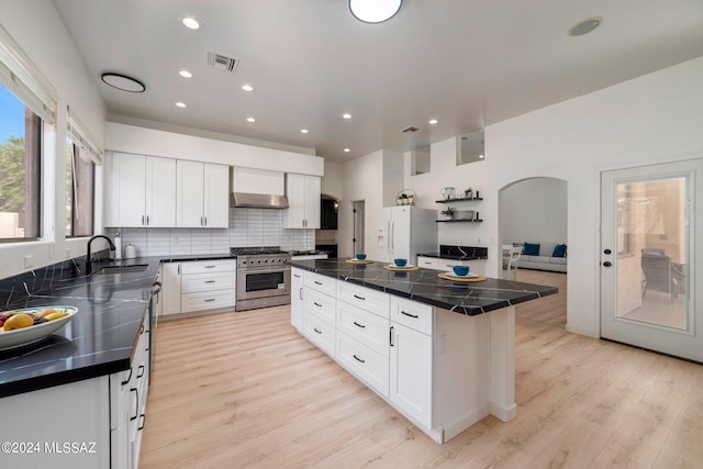 kitchen with white cabinets, a center island, stainless steel stove, and light hardwood / wood-style floors