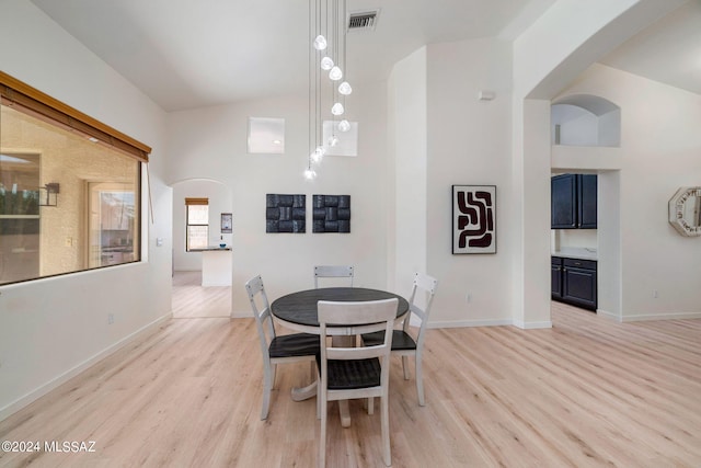 dining room featuring high vaulted ceiling and light hardwood / wood-style flooring