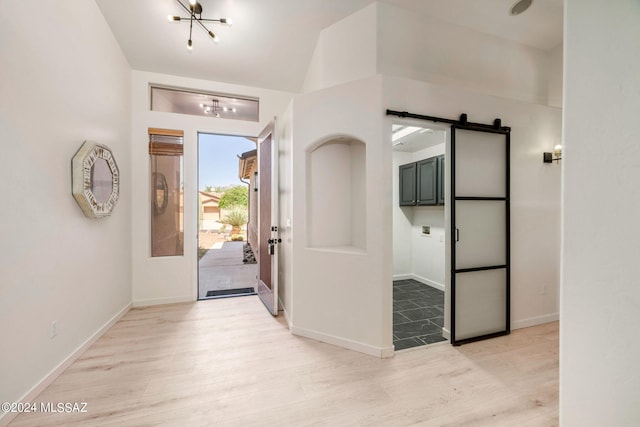 entrance foyer with a barn door, light hardwood / wood-style flooring, and vaulted ceiling