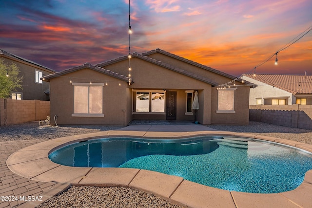 pool at dusk featuring a patio