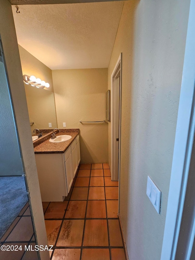 bathroom with tile patterned flooring, vanity, and a textured ceiling