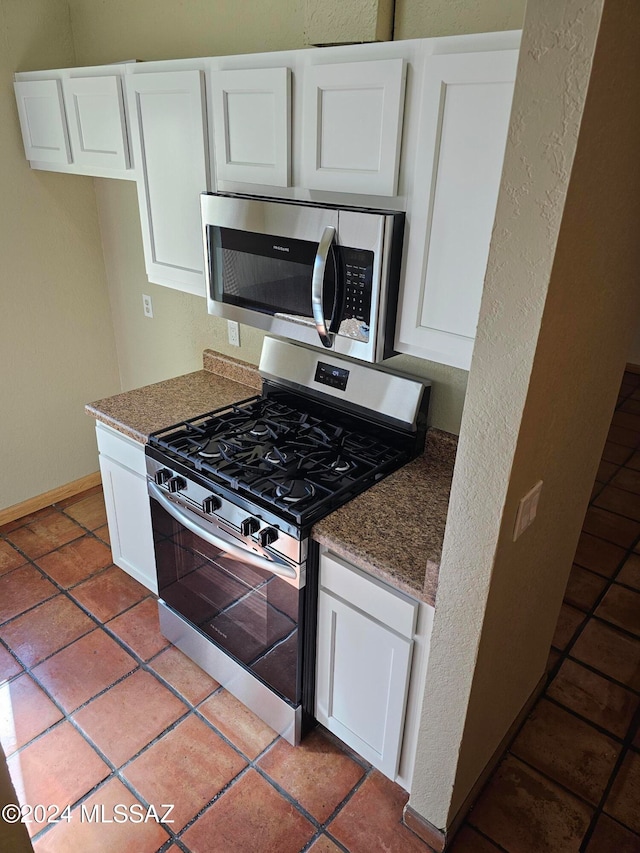 kitchen featuring dark stone countertops, white cabinets, and stainless steel appliances