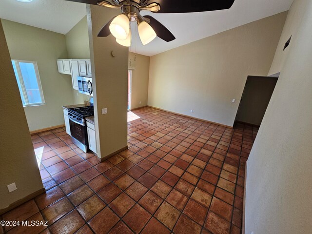 kitchen featuring white cabinets, vaulted ceiling, ceiling fan, dark tile patterned floors, and appliances with stainless steel finishes