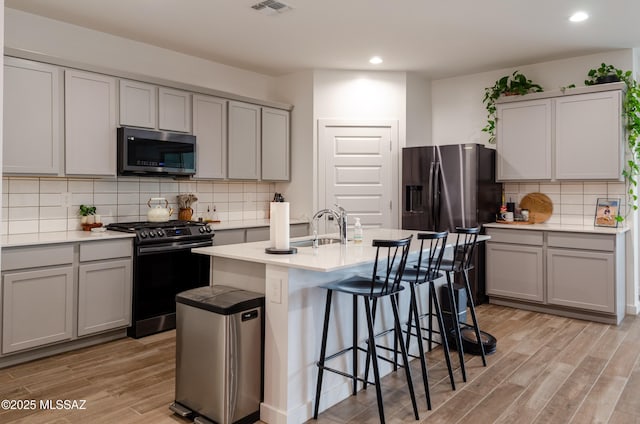 kitchen featuring sink, a breakfast bar area, light wood-type flooring, an island with sink, and stainless steel appliances