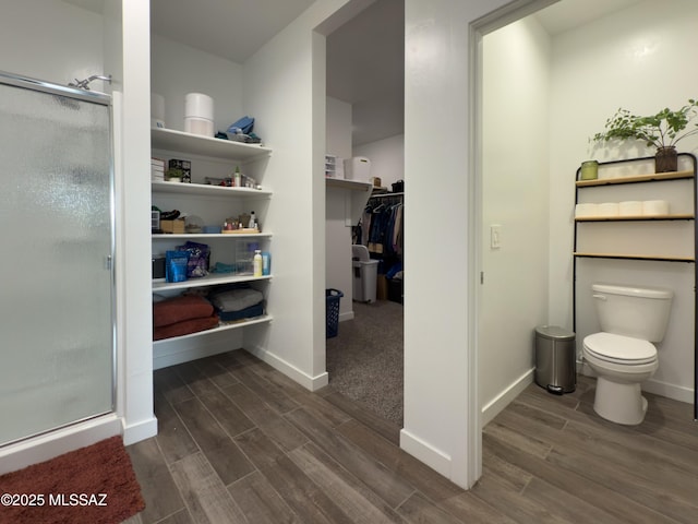 bathroom featuring a shower with shower door and toilet