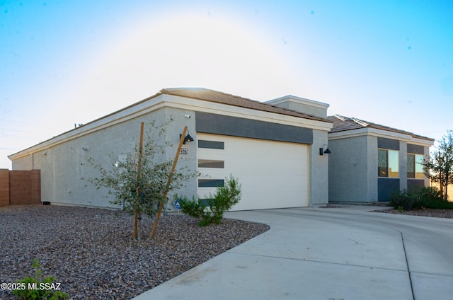 view of home's exterior with a garage, fence, concrete driveway, and stucco siding