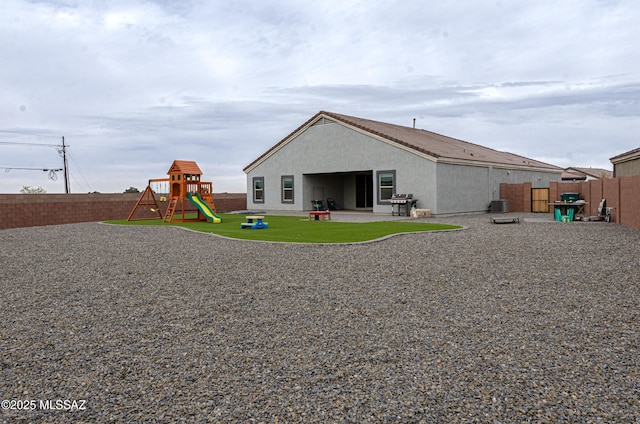 back of property with a patio area, a fenced backyard, stucco siding, and a playground