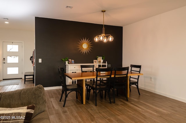 dining area featuring a notable chandelier, wood finished floors, visible vents, and baseboards