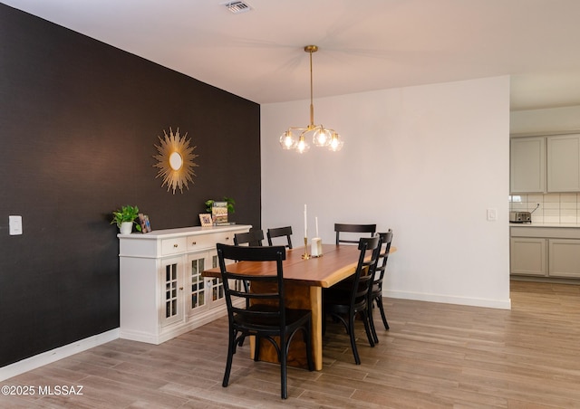 dining space featuring light hardwood / wood-style flooring and a chandelier