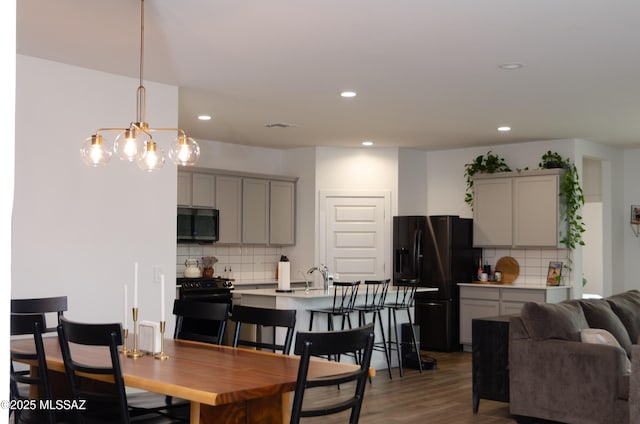 dining area with a notable chandelier, sink, and dark wood-type flooring