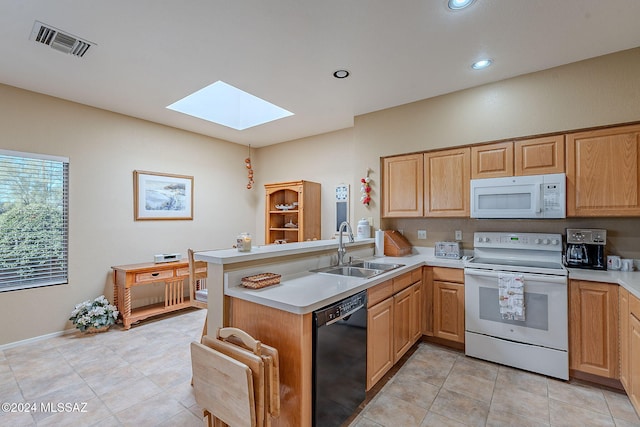 kitchen with kitchen peninsula, sink, a skylight, and white appliances